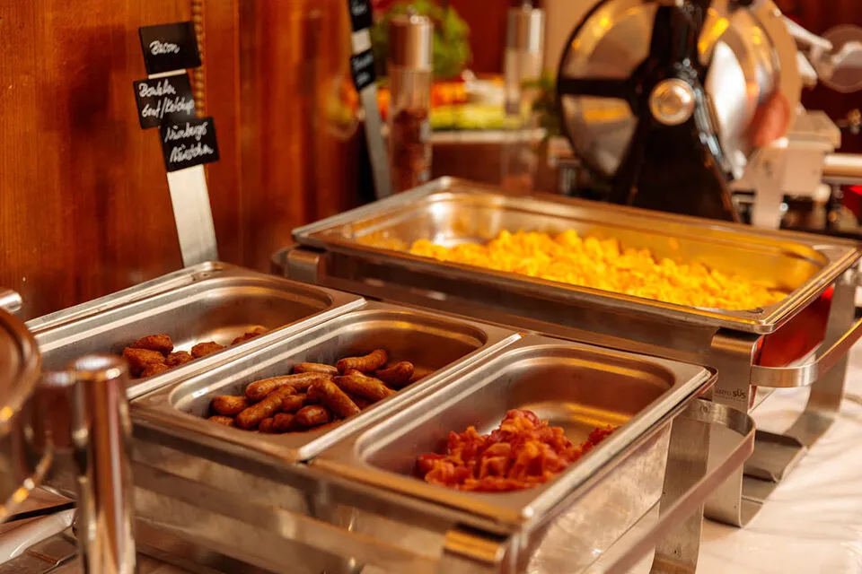 Warme Eierspeisen, Bratwürste und Bacon vom Frühstücksbuffet